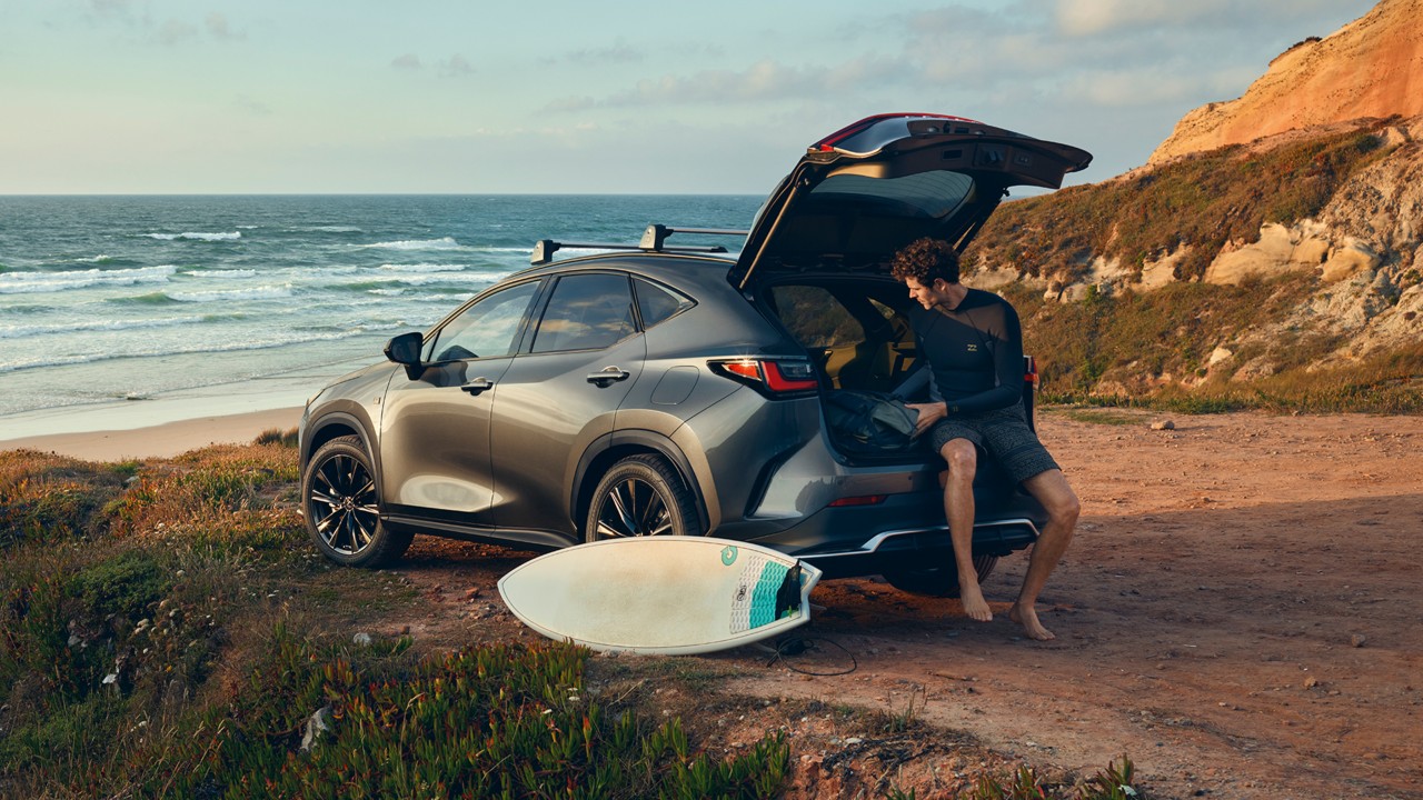 A man sat on the boot of the Lexus NX on the coast